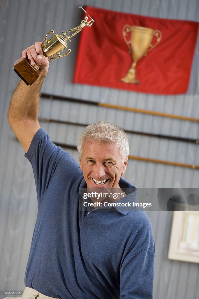 Man holding up trophy in victory
