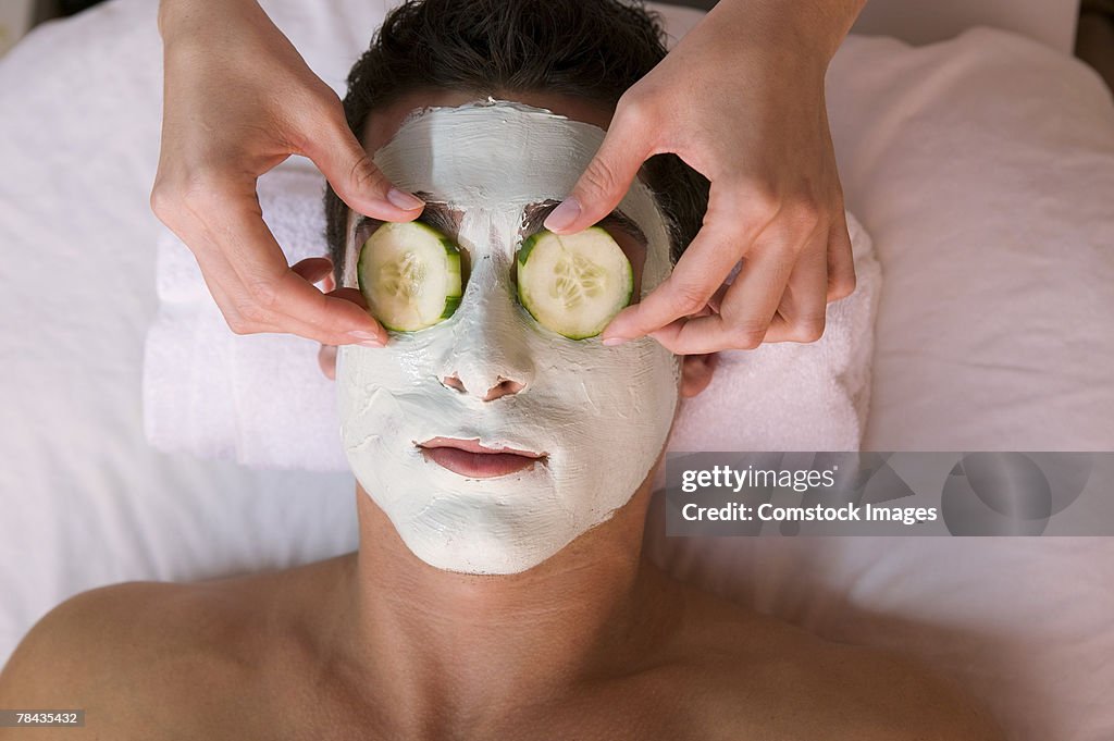 Man wearing facial mask and cucumber slices