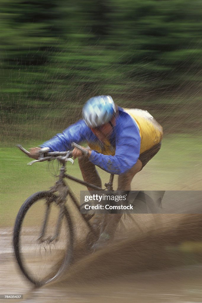 Man mountain biking through mud