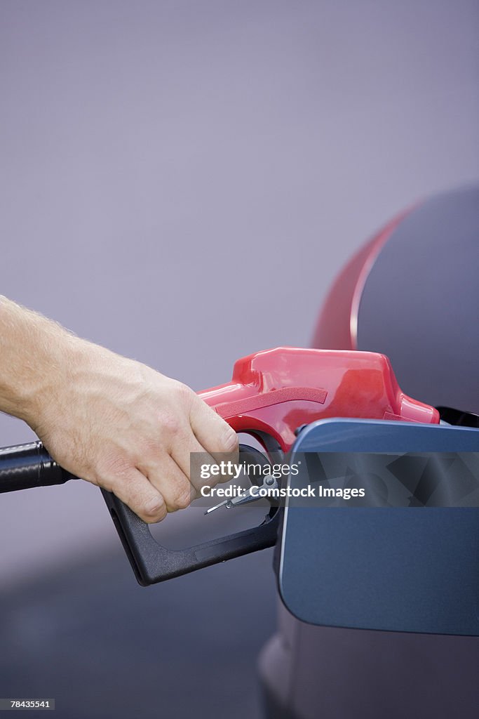 Hand pumping gas into vehicle