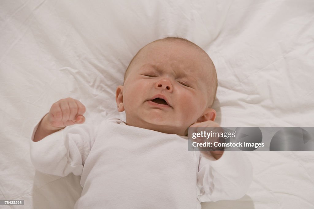Unhappy baby lying down with eyes closed