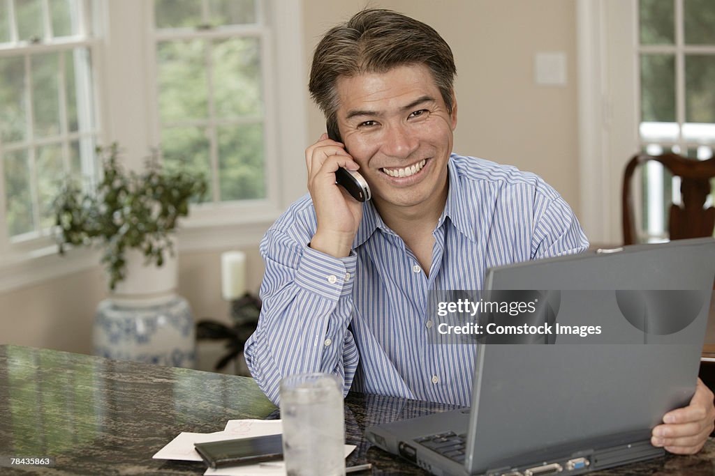 Man using laptop and talking on cell phone