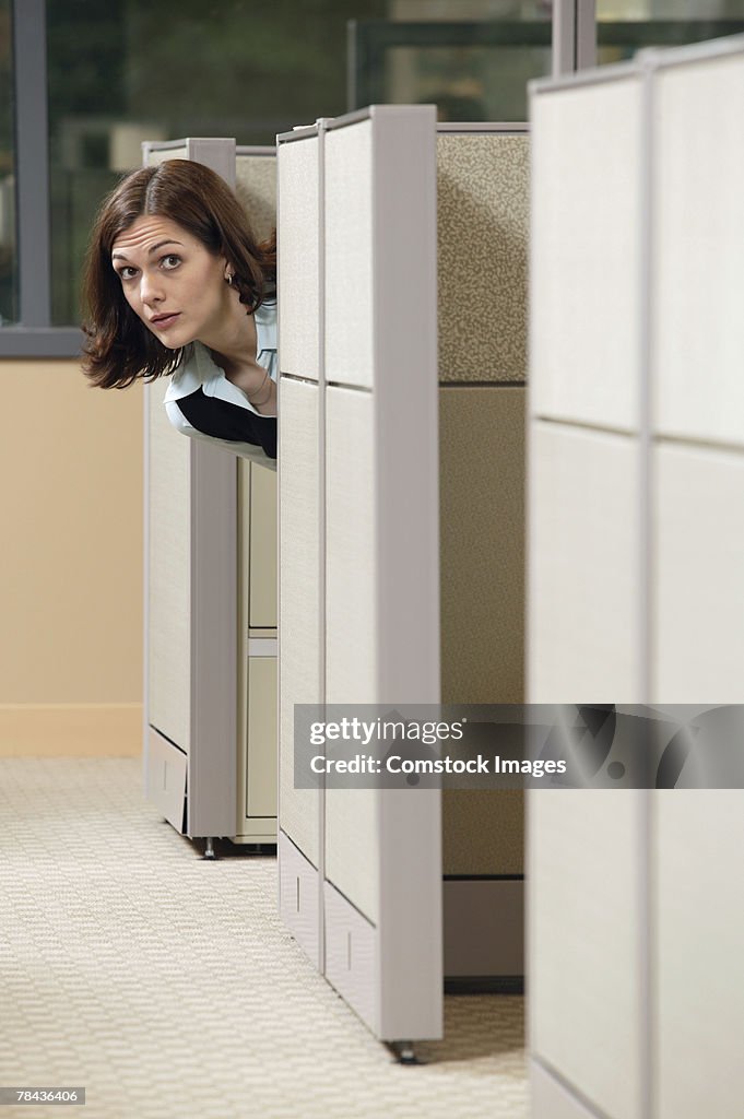 Businesswoman peeking out of cubicle