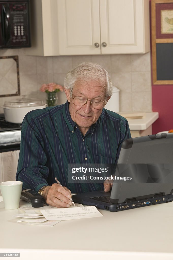 Man writing and using laptop