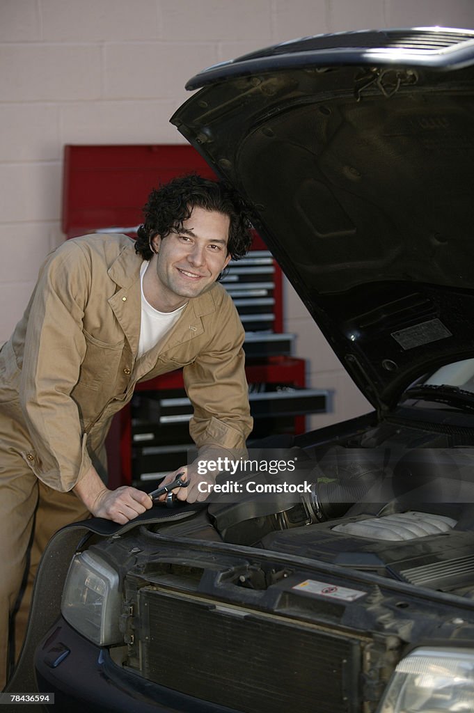 Mechanic posing with car in shop