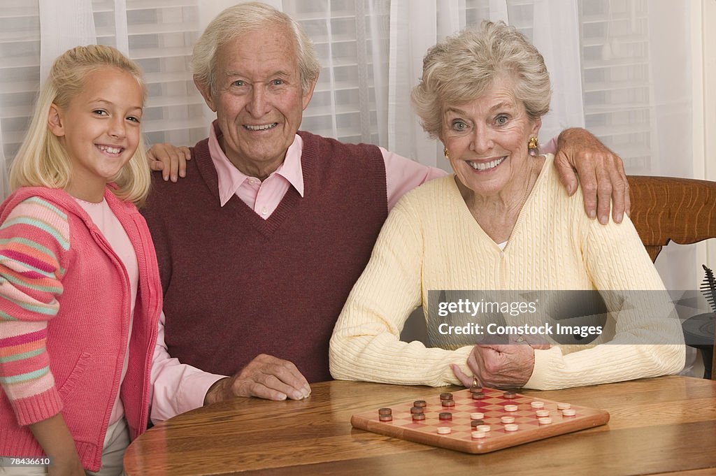 Grandparents playing checkers with granddaughter