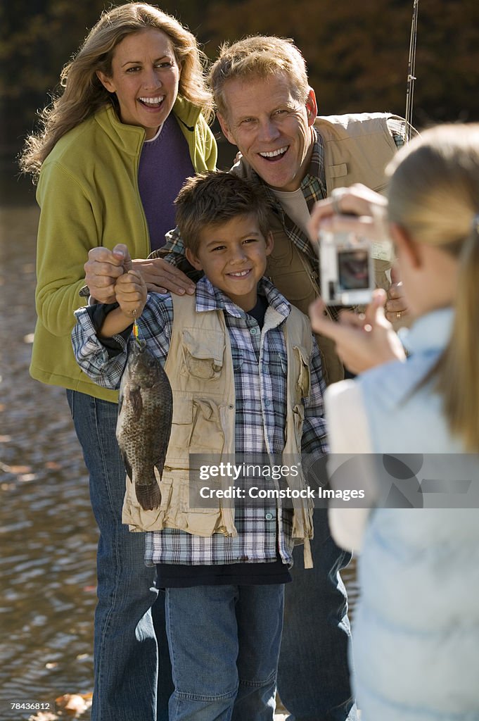 Girl taking photograph of family fishing