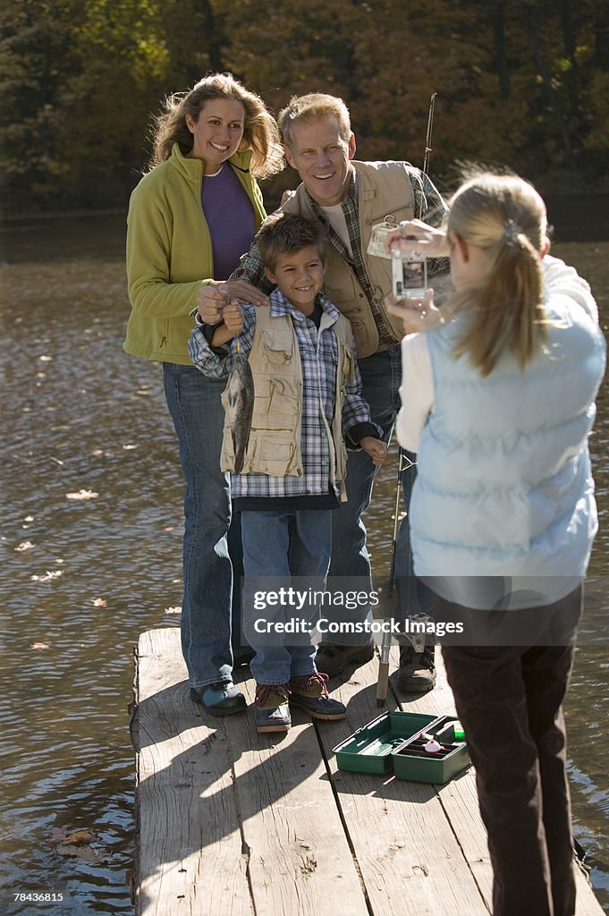 Girl taking photograph of family fishing