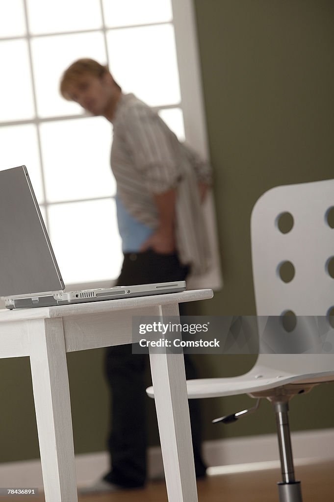 Man pacing and looking at laptop computer on table