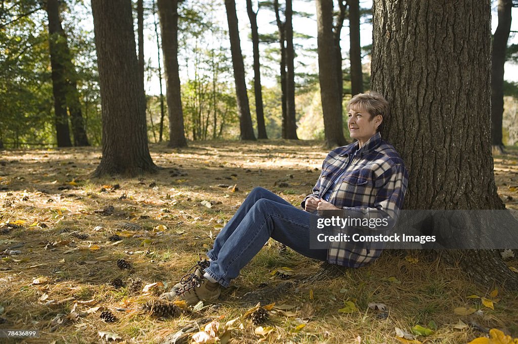 Woman resting against tree