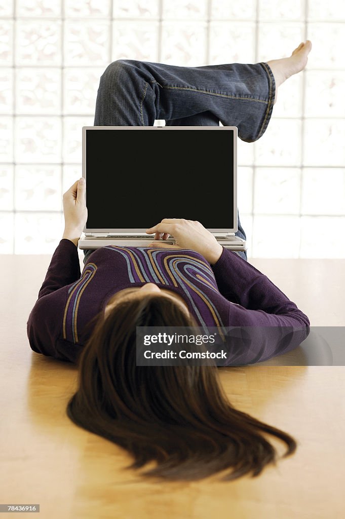 Woman lying on the floor and using laptop computer