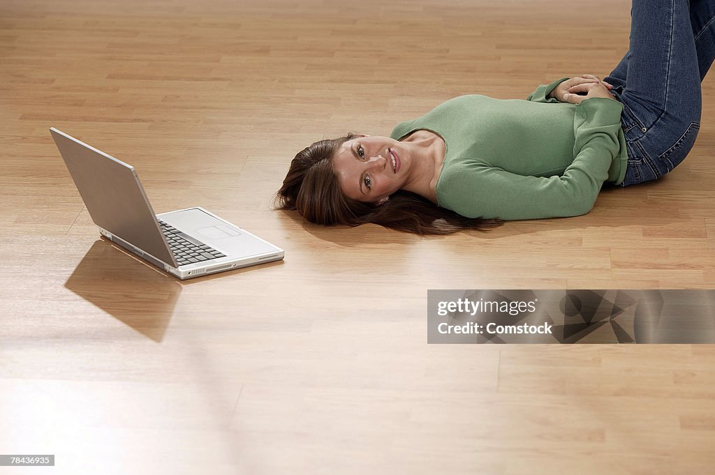 Woman lying on floor next to laptop computer