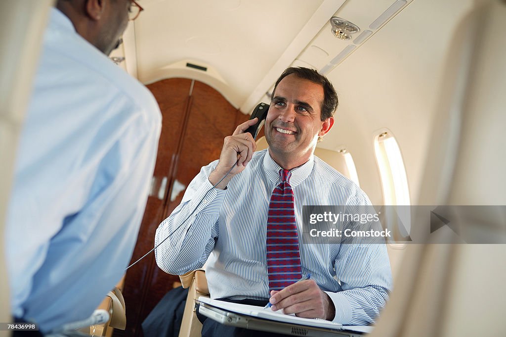 Businessman talking on cell phone in private jet