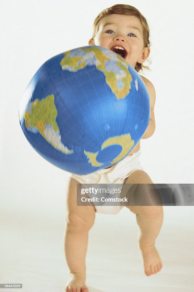 Baby in diapers holding inflatable globe