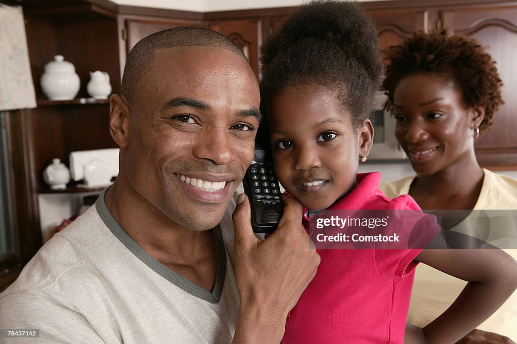 Father sharing telephone with daughter