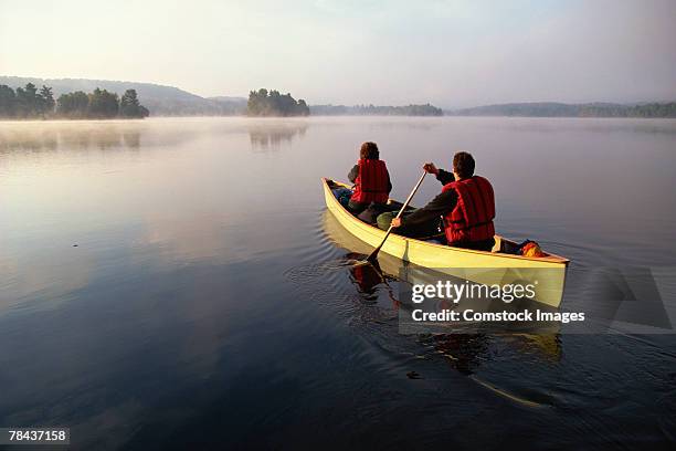 people canoeing on lake - two people canoeing on a lake stock pictures, royalty-free photos & images