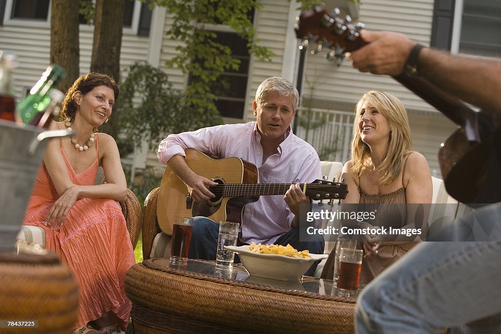 Friends conversing and playing guitar at a party