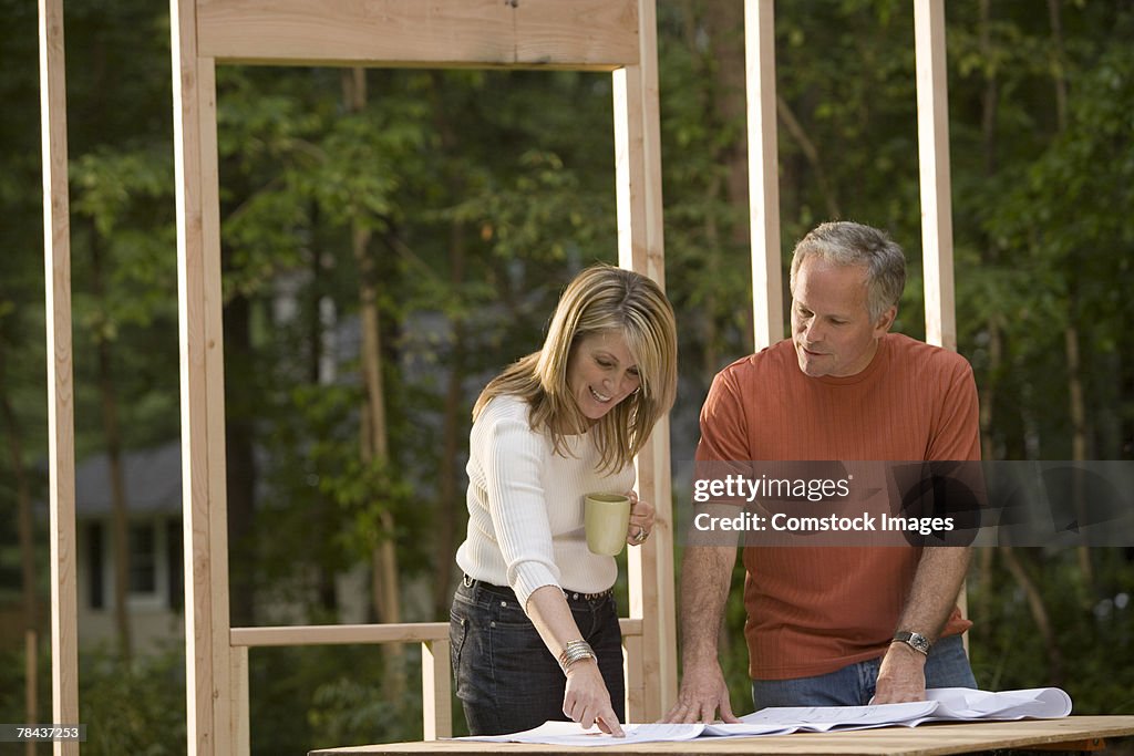 Couple reviewing blueprints at construction site