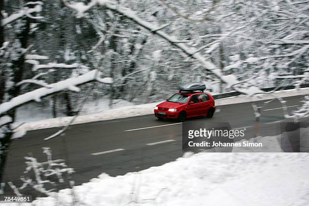 Car moves along a road leading through a snow covered forest on December 13, 2007 near Steingaden, Germany. Snowfall brought winter back to the...