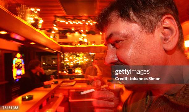 Peter Wolf, Innkeeper of the pub "3 Gloecklein" smokes a cigarette behind the bar on December 13, 2007 in Munich, Germany. The Bavarian Parliament...