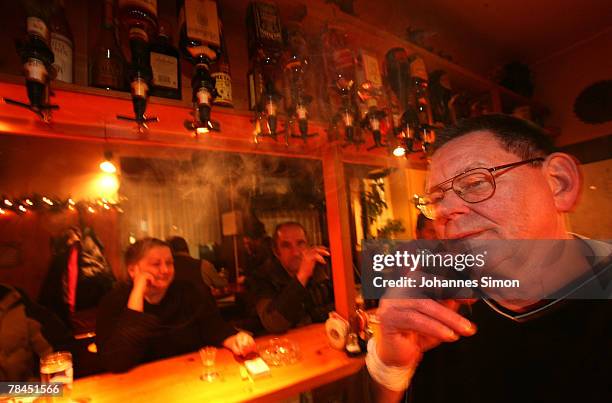 Gerd Germer , Innkeeper of the pub "Zur Westermuehle" smokes a cigar behind the bar on December 13, 2007 in Munich, Germany. The Bavarian Parliament...