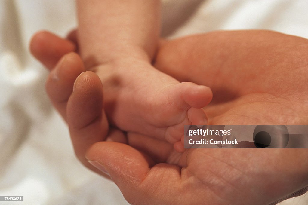 Adult hand holding baby's foot