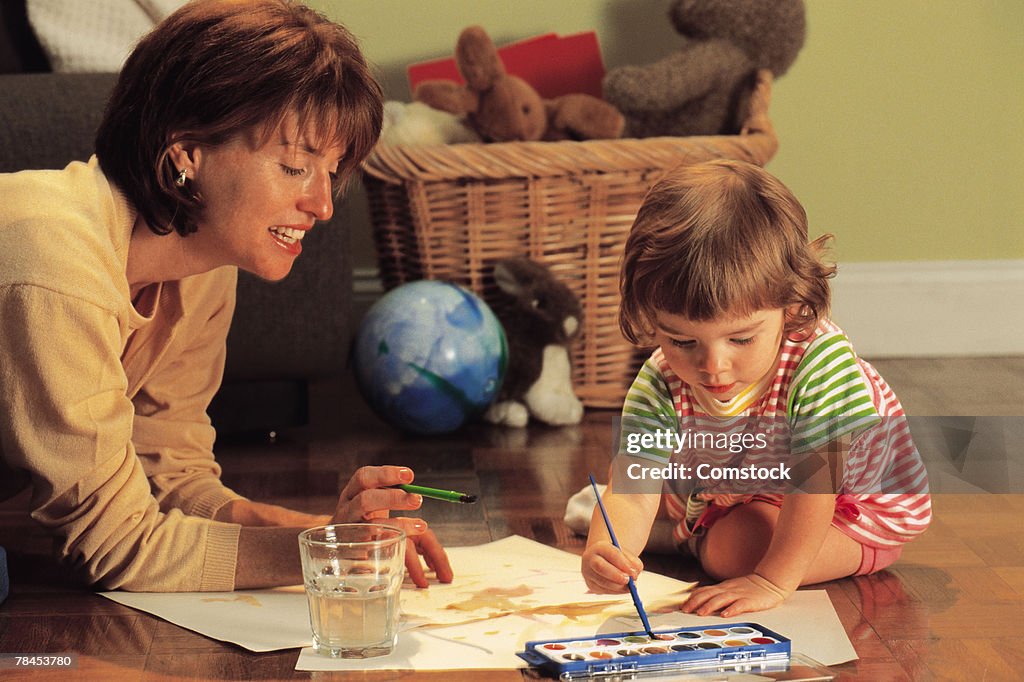 Mother and daughter painting with watercolors on floor