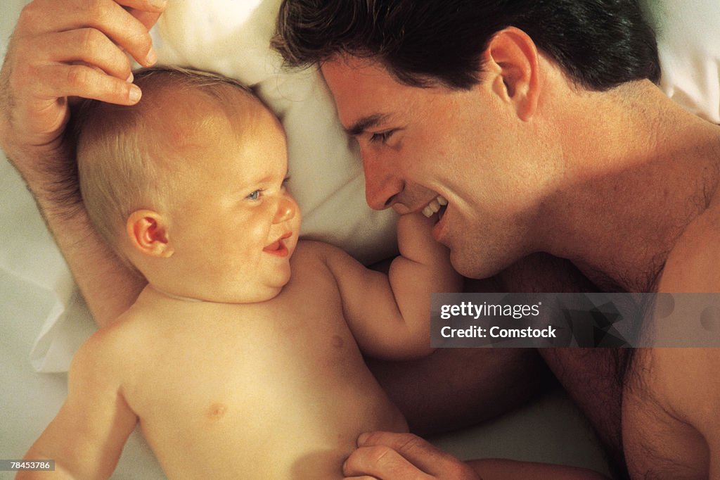 Father cuddling with baby in bed