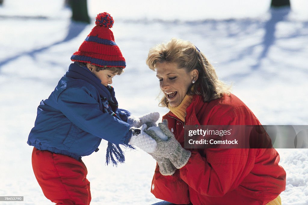 Mother and child outdoors making a snowball