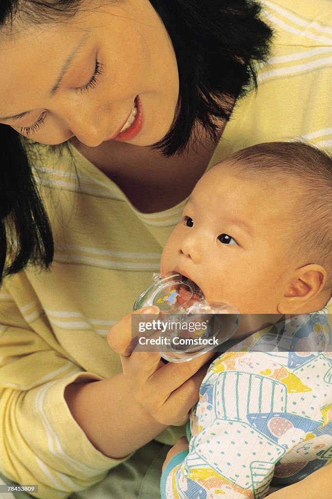 Mother holding teething ring in baby's mouth