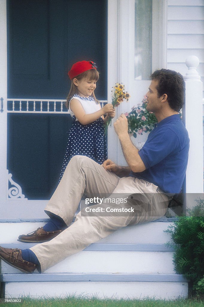 Father on porch receiving flowers from daughter