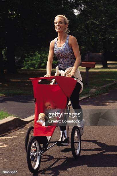 mother pushing baby in stroller - three wheeled pushchair stock pictures, royalty-free photos & images