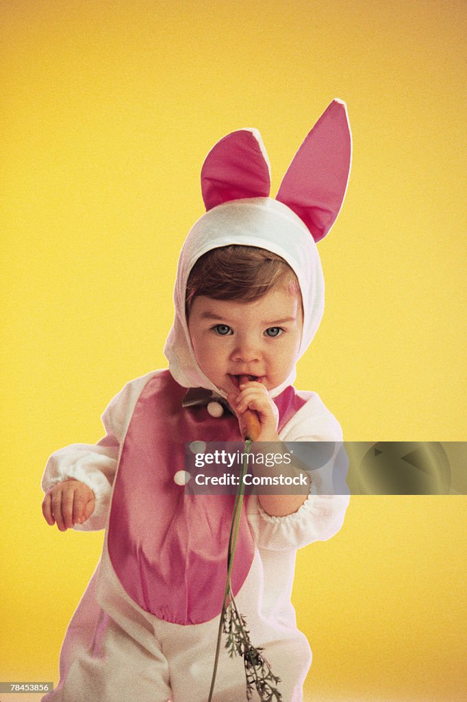 Toddler in a bunny costume holding a carrot