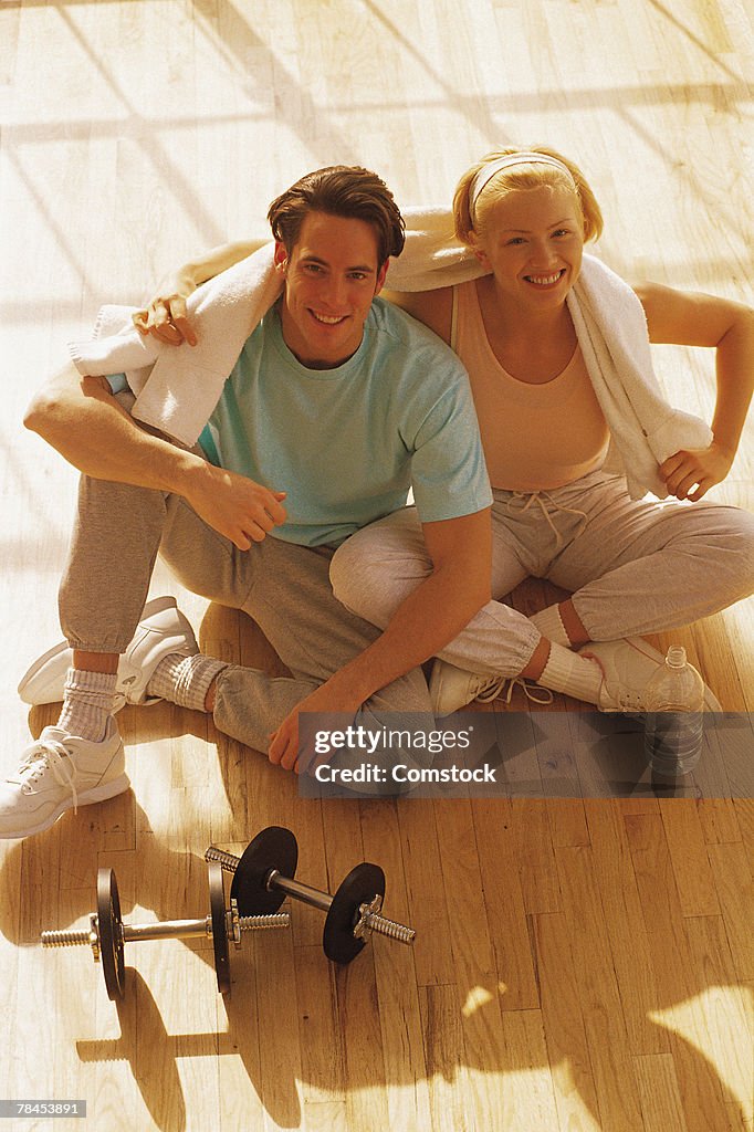 Couple sitting on floor with dumbbells