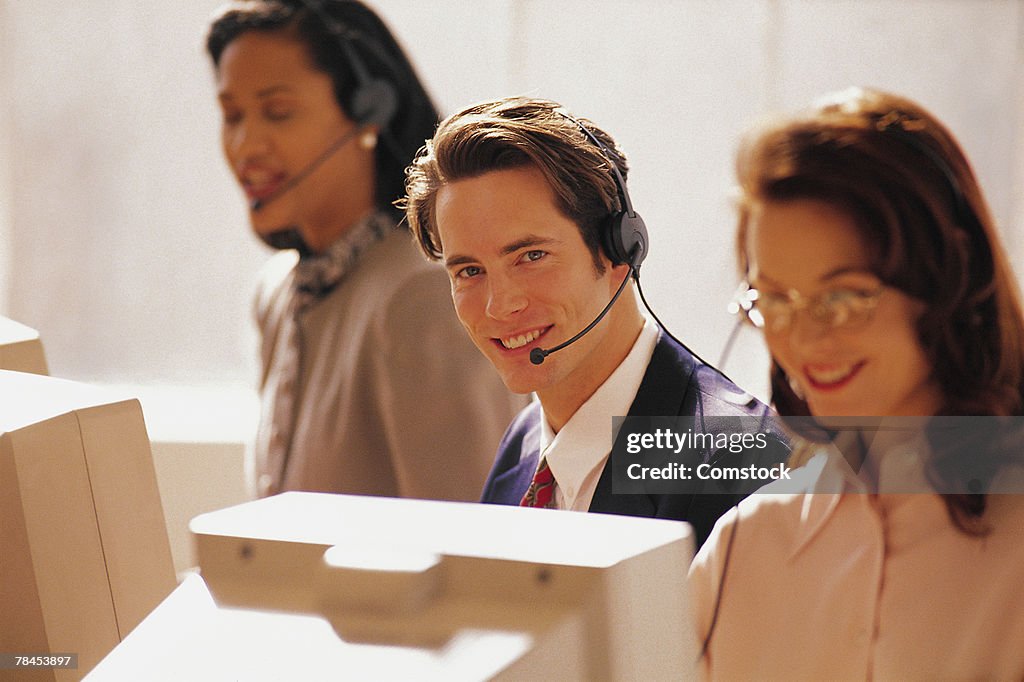 Man wearing headset at computer with others