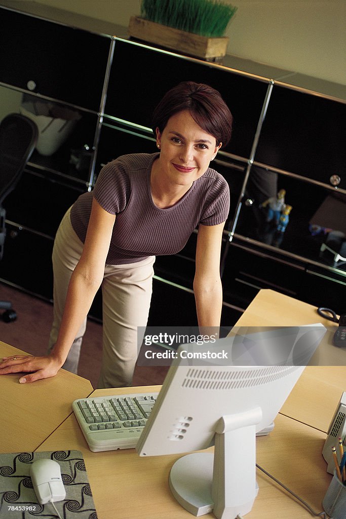 Woman standing behind computer at desk