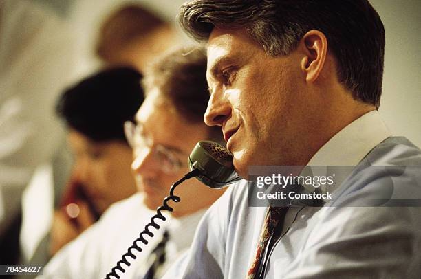 businessman on telephone in room with others - unhappy salesman stock pictures, royalty-free photos & images