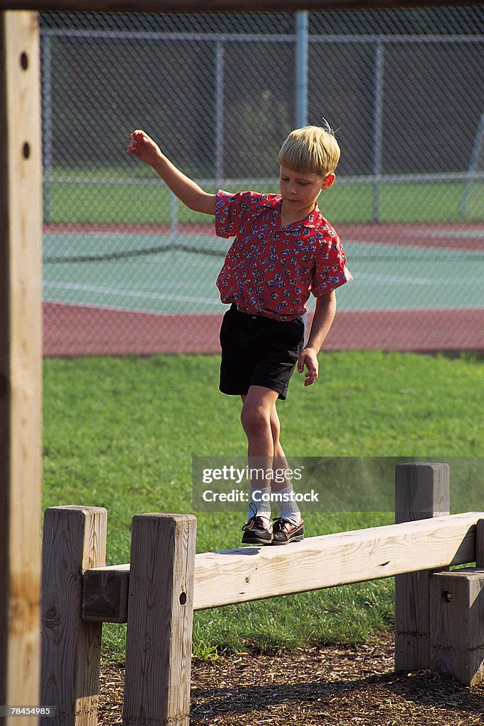 Boy walking on balance beam at a park