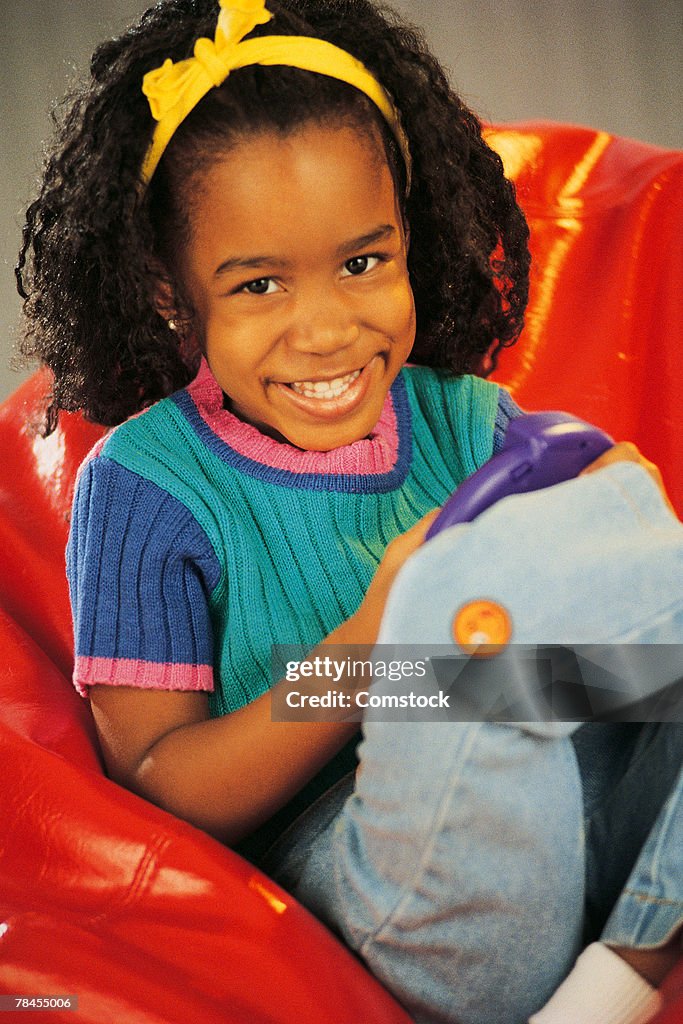 Girl sitting in bean bag chair with video game controls