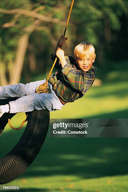 boy swinging on tire swing - tire swing stock pictures, royalty-free photos & images