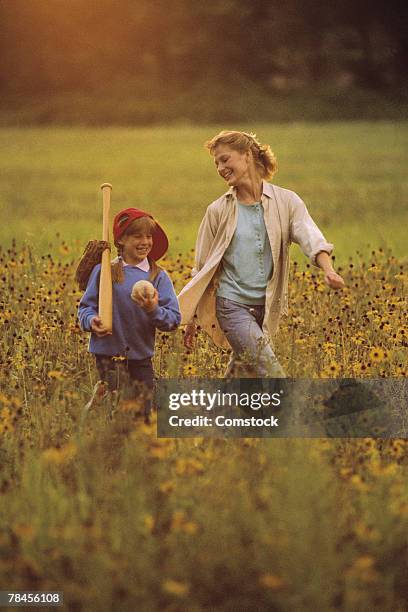 mother and daughter walking through field - baseball mom stockfoto's en -beelden