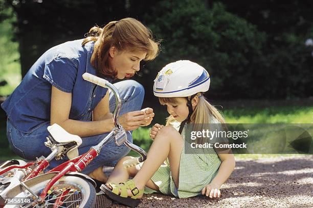 mother tending to daughter who fell off bike - girl bike stock pictures, royalty-free photos & images