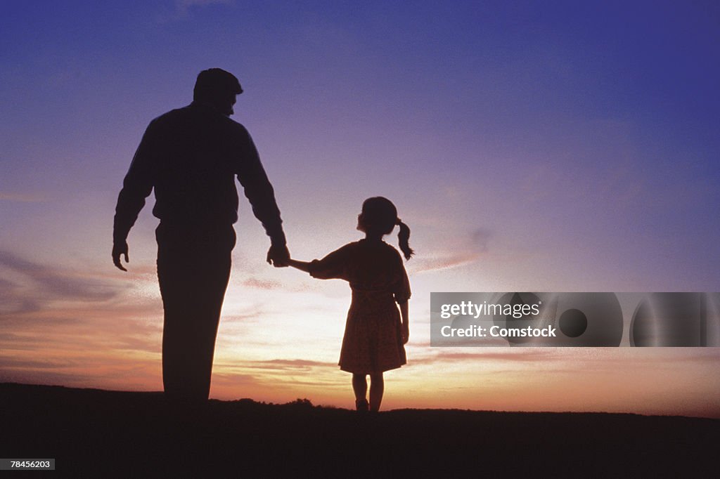 Silhouette of father and daughter walking