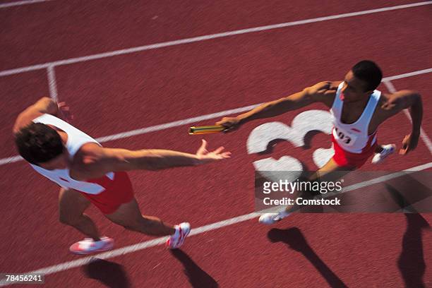 men passing baton in relay race - staffel stock-fotos und bilder