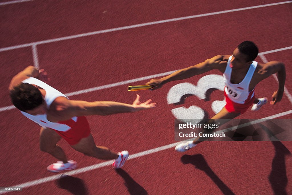 Men passing baton in relay race