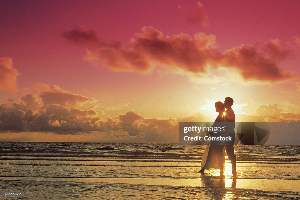 Couple posing on beach at sunset