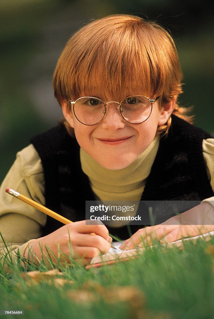 Boy doing homework in grass