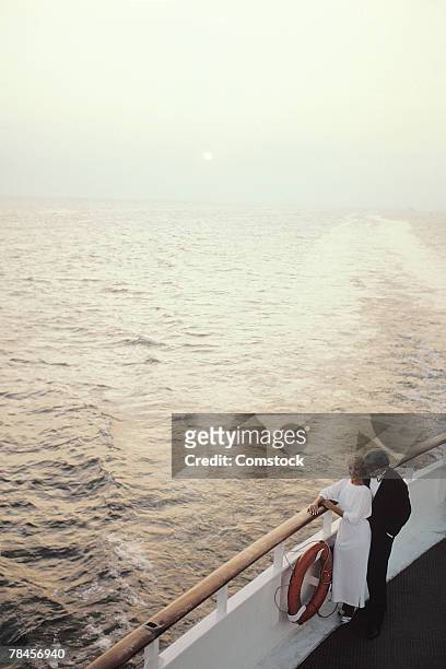 romantic couple enjoying view from deck of cruise ship - railing stockfoto's en -beelden