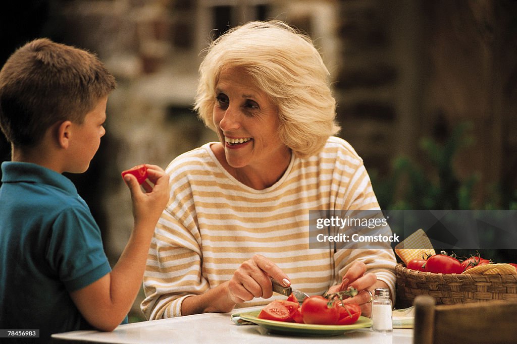 Grandmother with grandson while cutting tomatoes