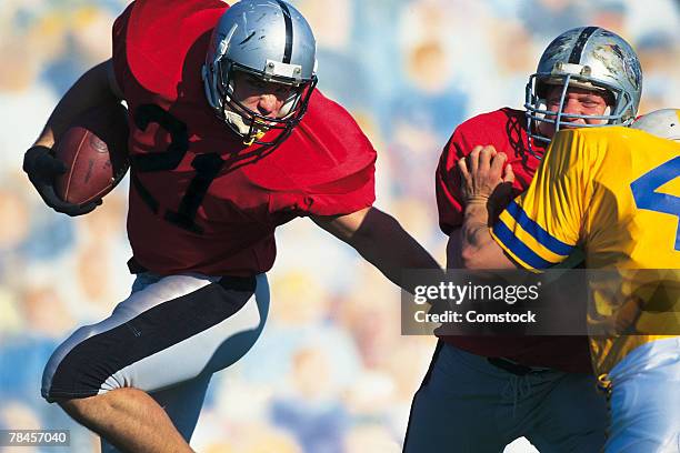 running back avoiding defender in football game - rush american football stockfoto's en -beelden